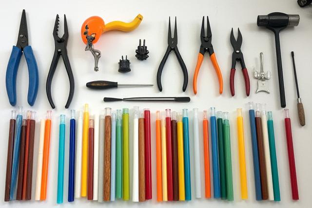 Ein aufgeräumter Arbeitsbereich mit verschiedenen Glasbläserwerkzeugen und Farbstäben, bereit für die Anwendung